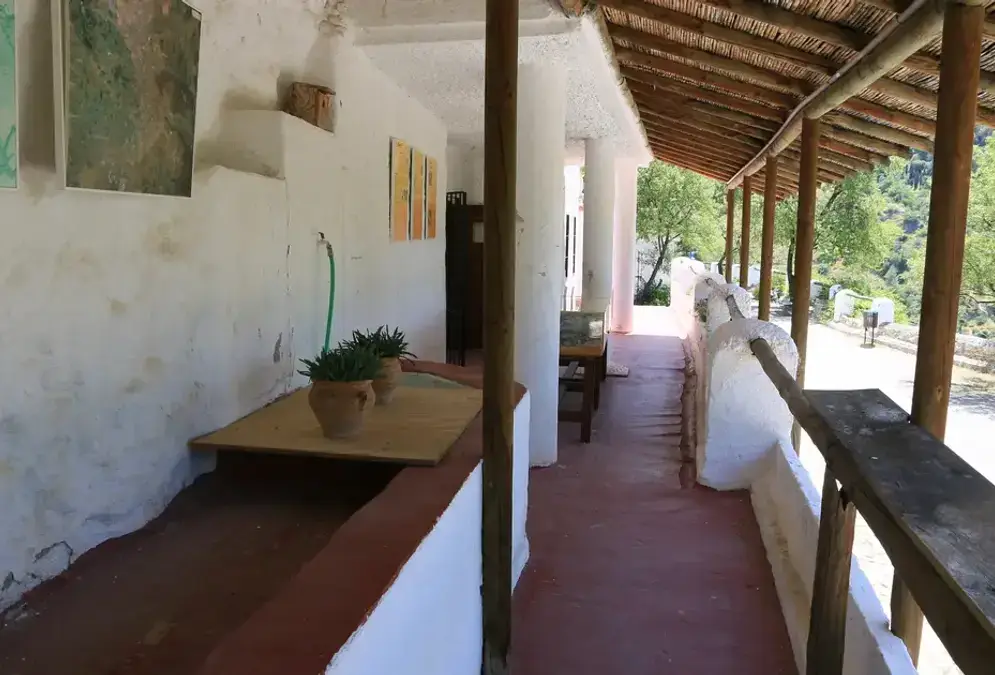 Interior of a restored cave dwelling at the Sacromonte Cave Museum in Granada, showing traditional furniture and copper pots